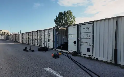 Base33 in Wien-Floridsdorf: eine Reihe Container, einer offen, davor Kettlebells. Standbild aus dem Kampagnenvideo